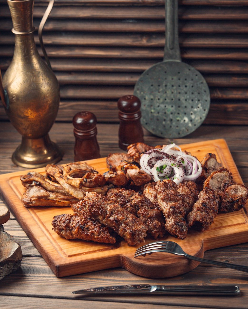 Kofte, shish and chicken off the charcoal on a wooden board with sliced onions